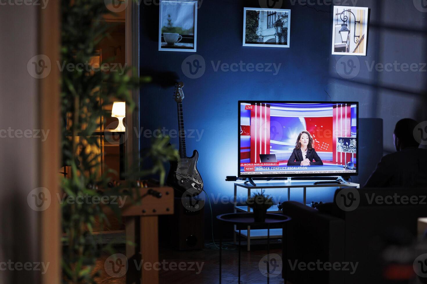 Relaxed person watching breaking news on television at night, chilling on sofa in living room and watching tv program. Young adult listening to media information on global network. photo