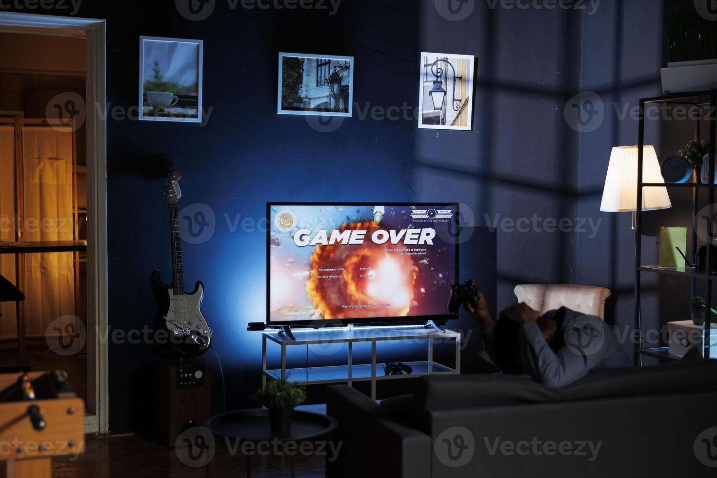 Player is dissatisfied after failing to win shooter tournament while engaging in web based multiplayer battle at night. Unhappy adult playing first person online action games on home television. photo
