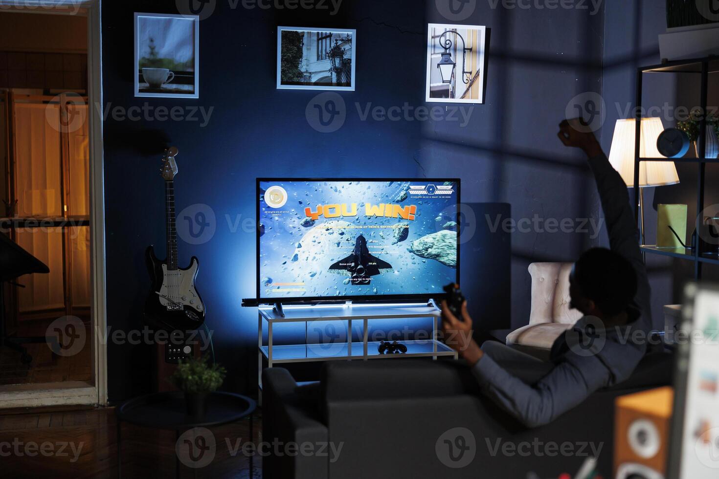 Enthusiastic player having fun winning shooting tournament on tv in the living room. Adult feels delighted after successful win of online first person perspective contest during his free time. photo