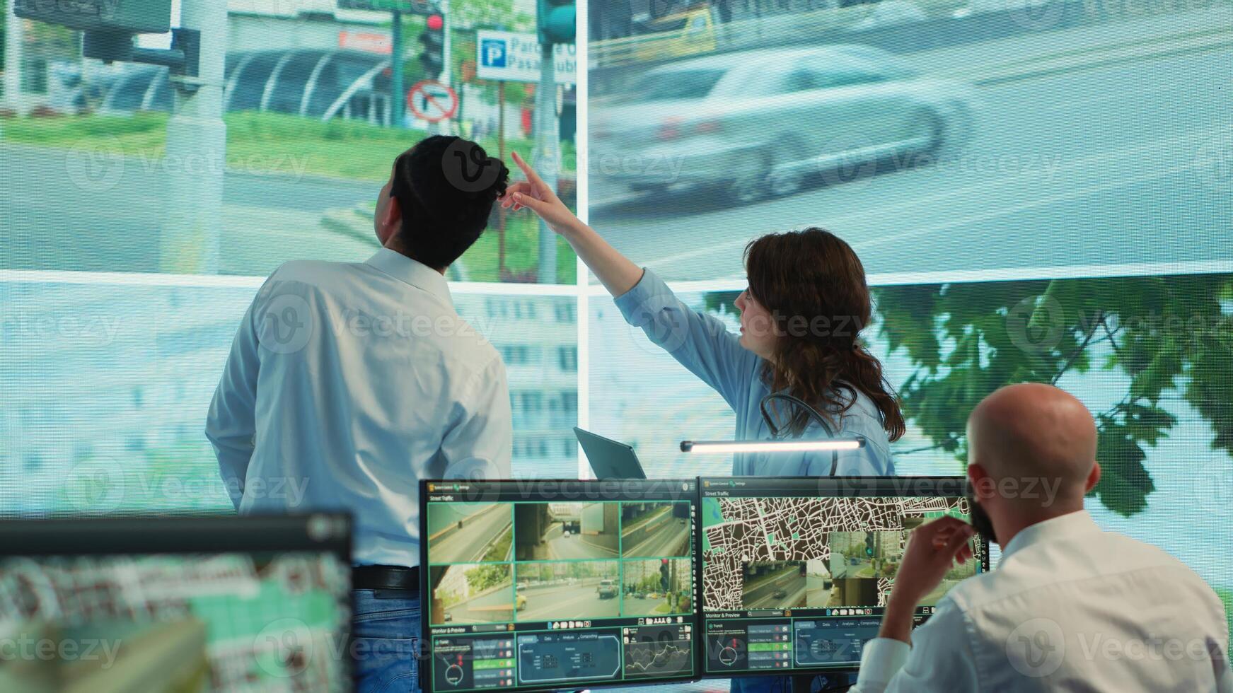 Diverse employees monitoring traffic via radar cameras at stop lights, using surveillance CCTV footage sensors in the city. People tracking cars in the government database, public safety. Camera A. photo