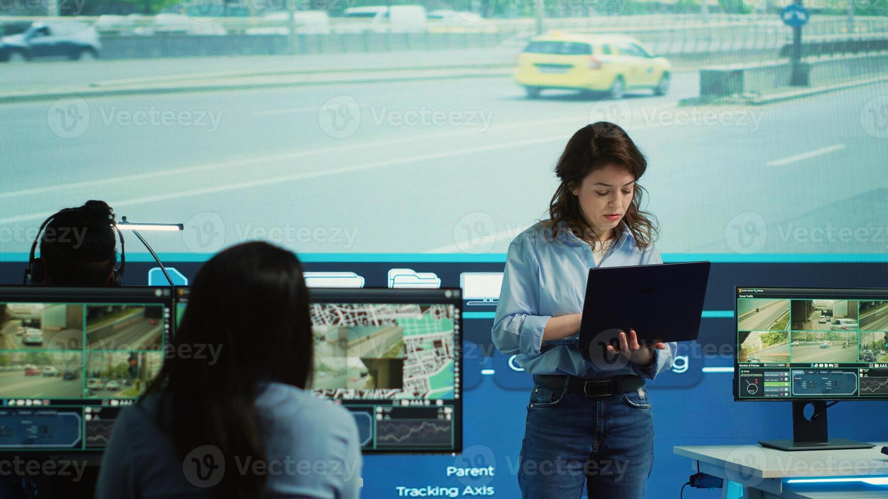 Young manager analyzing traffic surveillance data with her employees team, using the CCTV security system around the city. Agency experts employing satellite radars for reconnaissance. Camera A. photo