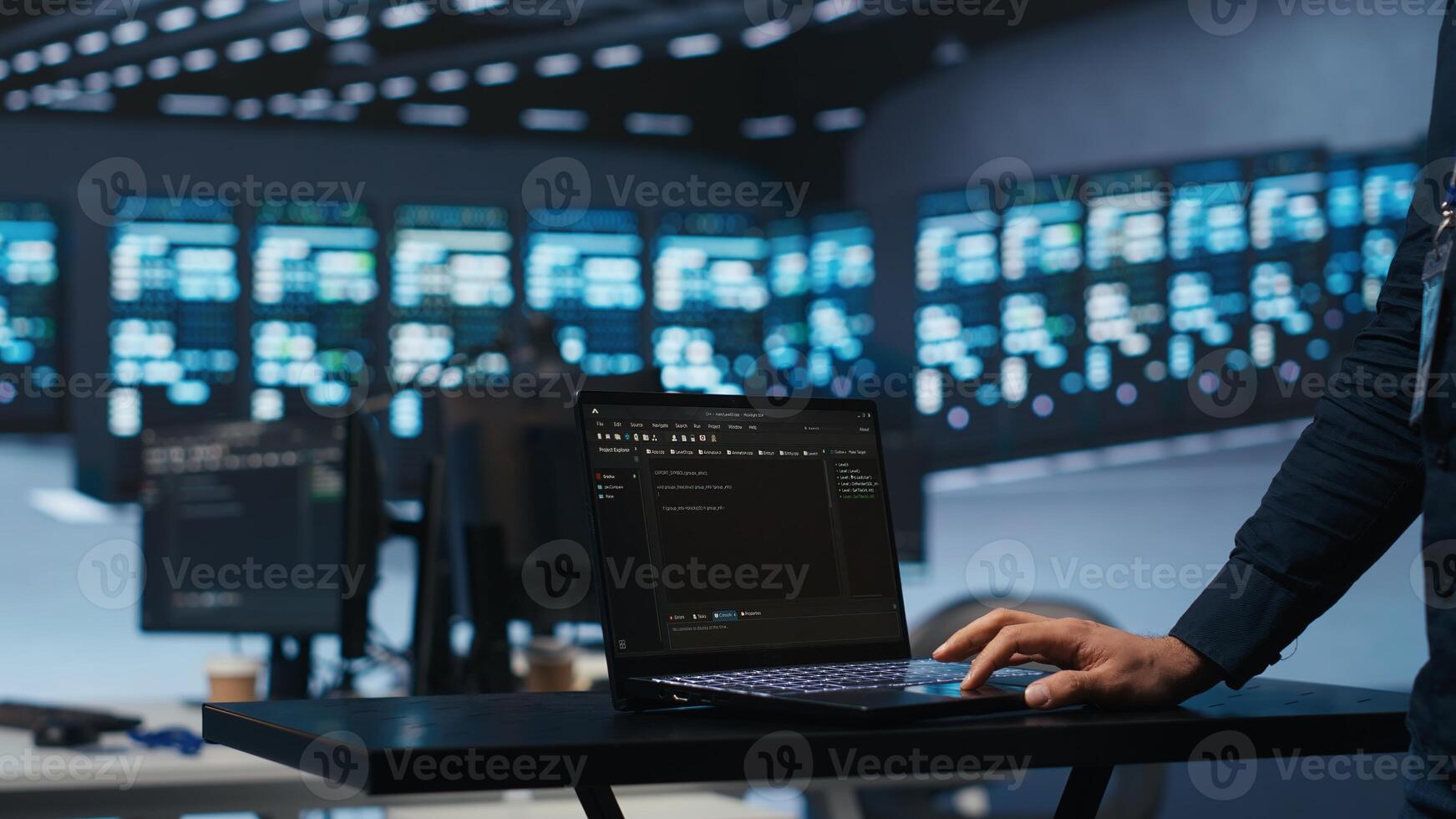 IT support employee writing code on laptop in high tech facility with server rows providing computing resources for different workloads. System administrator uses notebook to oversee supercomputers photo