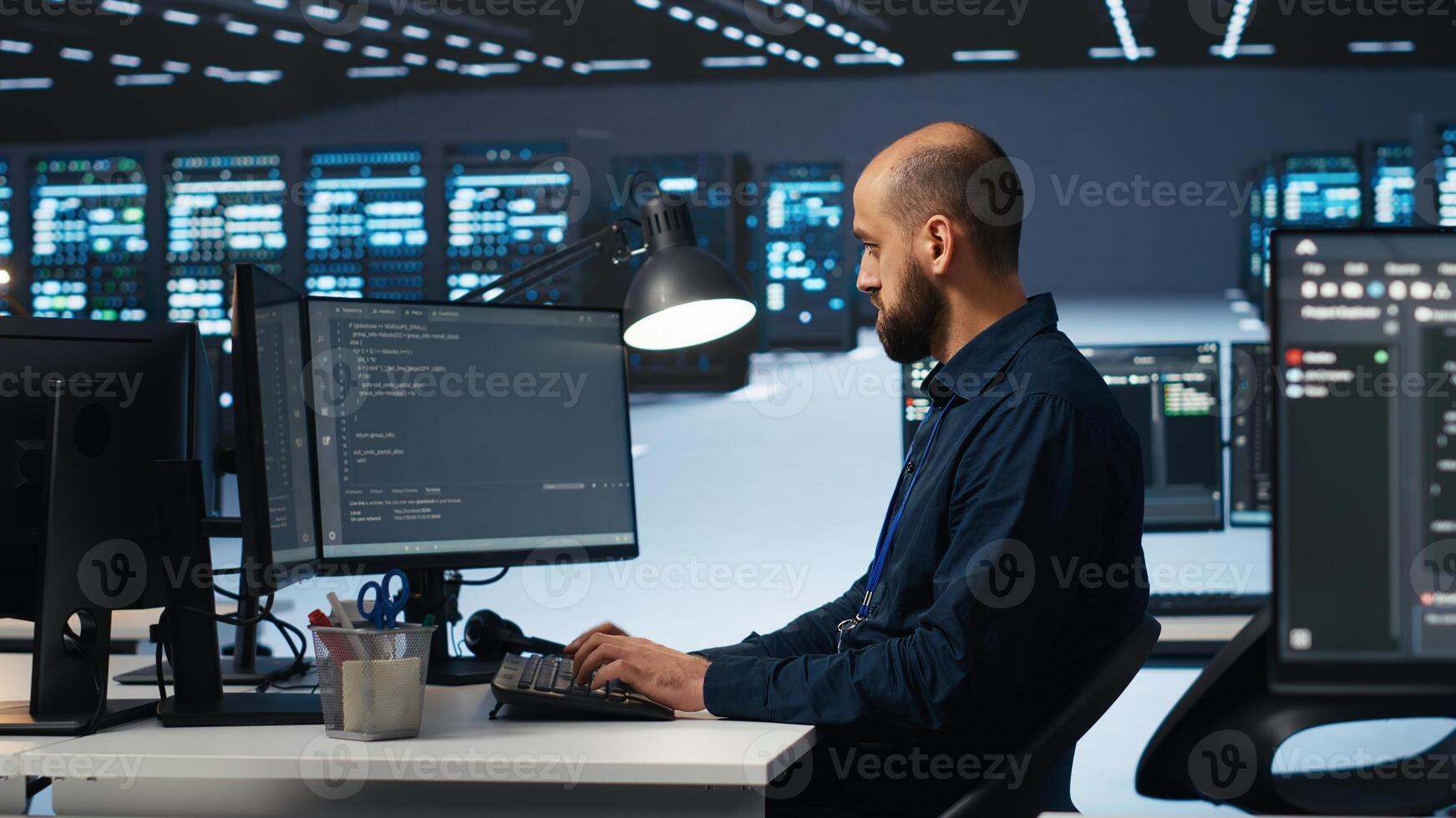 IT engineer programming in server hub housing advanced equipment storing massive datasets. Technician typing code on computer to mend data center racks doing complex computational operations photo