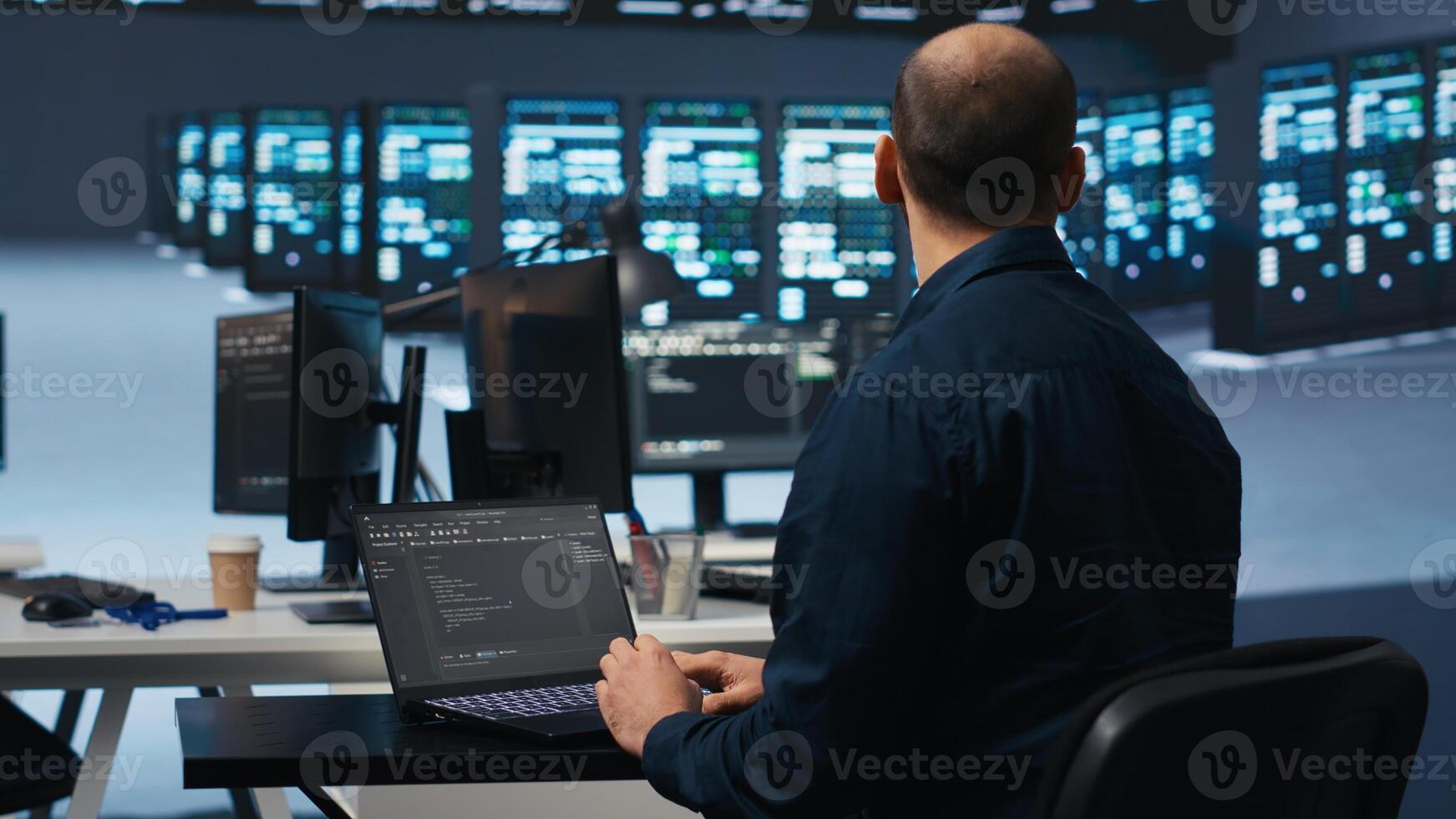 Computer scientist using laptop device to do programming in data center room housing servers . IT supervisor writing code on notebook to mend data storage facility racks doing computational operations photo