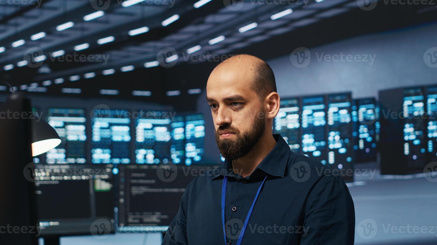 Computer scientist programming in data center room housing blade servers storing datasets. IT professional writing code on PC to mend data storage facility racks doing complex computational operations photo