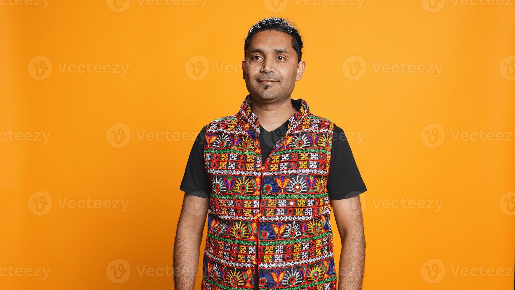 Portrait of cheerful friendly indian man smiling, looking pleased, isolated over studio background. Happy expressive asian person in traditional attire grinning, feeling satisfied, camera B photo
