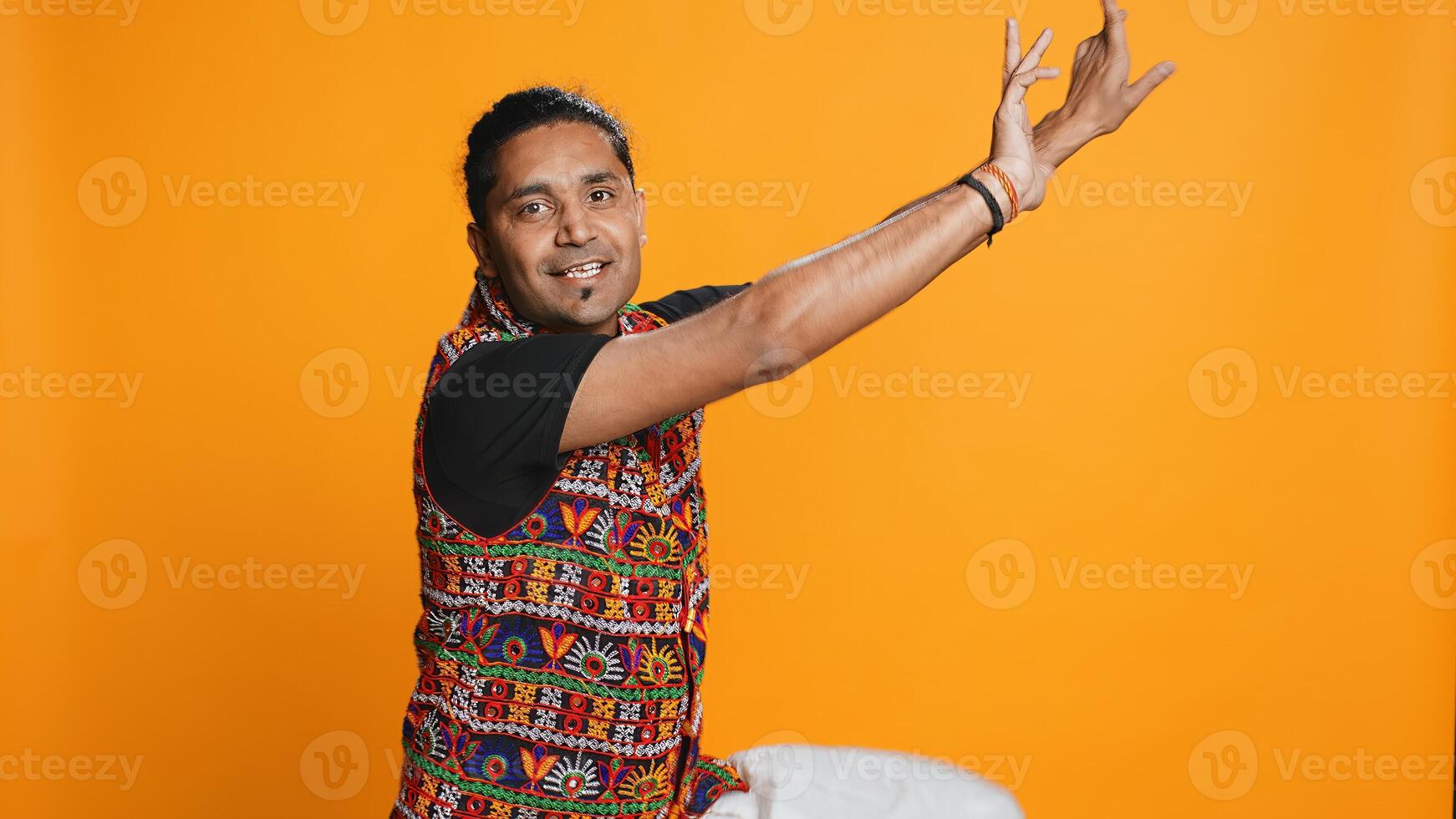 Joyful person having fun, dancing on rhythm, enjoying days off from work. Upbeat indian man entertaining himself doing funky movements, swinging arms, studio background, camera B photo