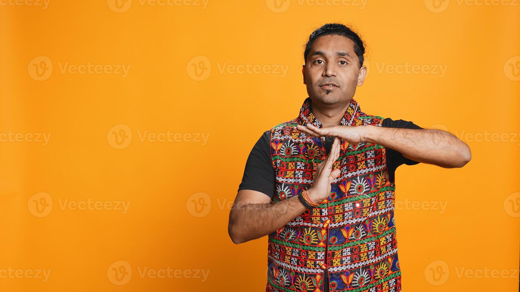 Portrait of assertive indian man asking for timeout, doing hand gestures, feeling fatigued. Firm person doing vehement pause sign gesturing, wishing for break, studio background, camera B photo