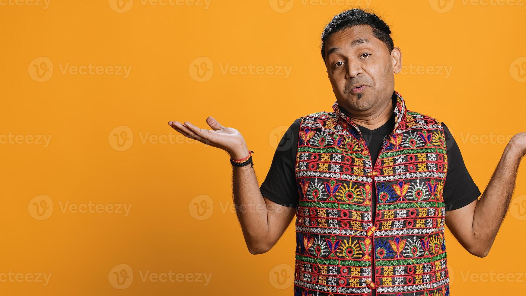 Indian man shrugging shoulders, unable to provide answer, having detached apathy facial expression. Apathetic person doing hand gesturing showing lack of knowledge, studio background, camera A photo