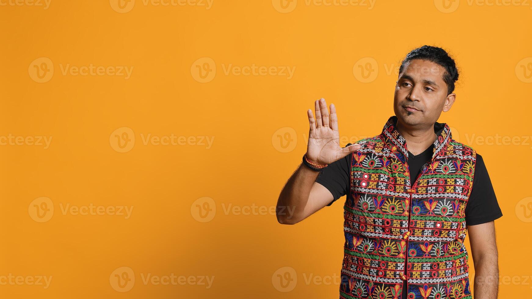 Indian man trying to stop chaotic fight using calming hand gesture to diffuse tensions, doing peaceful resolution. Reassuring person doing calm down sign gesturing, studio background, camera A photo