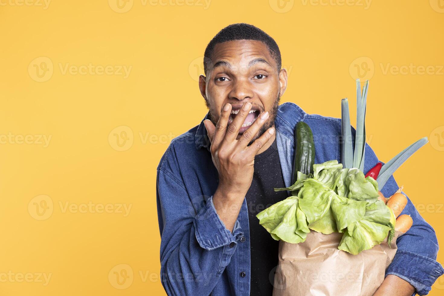 Joyful positive model feeling satisfied with fresh groceries in a paper bag, supporting vegan nutrition and ethically sourced food. Optimistic bio enthusiast enjoys natural organic veggies. photo