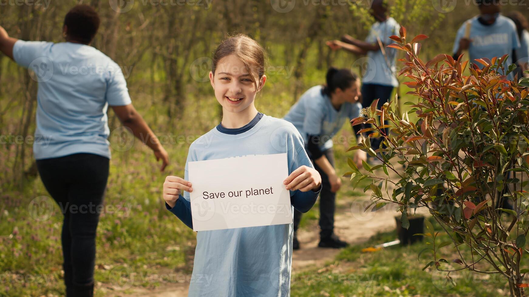 Portrait of sweet girl with save our planet poster against pollution and illegal dumping, volunteering to restore and preserve nature in the forest. Little child shows awareness sign. Camera A. photo