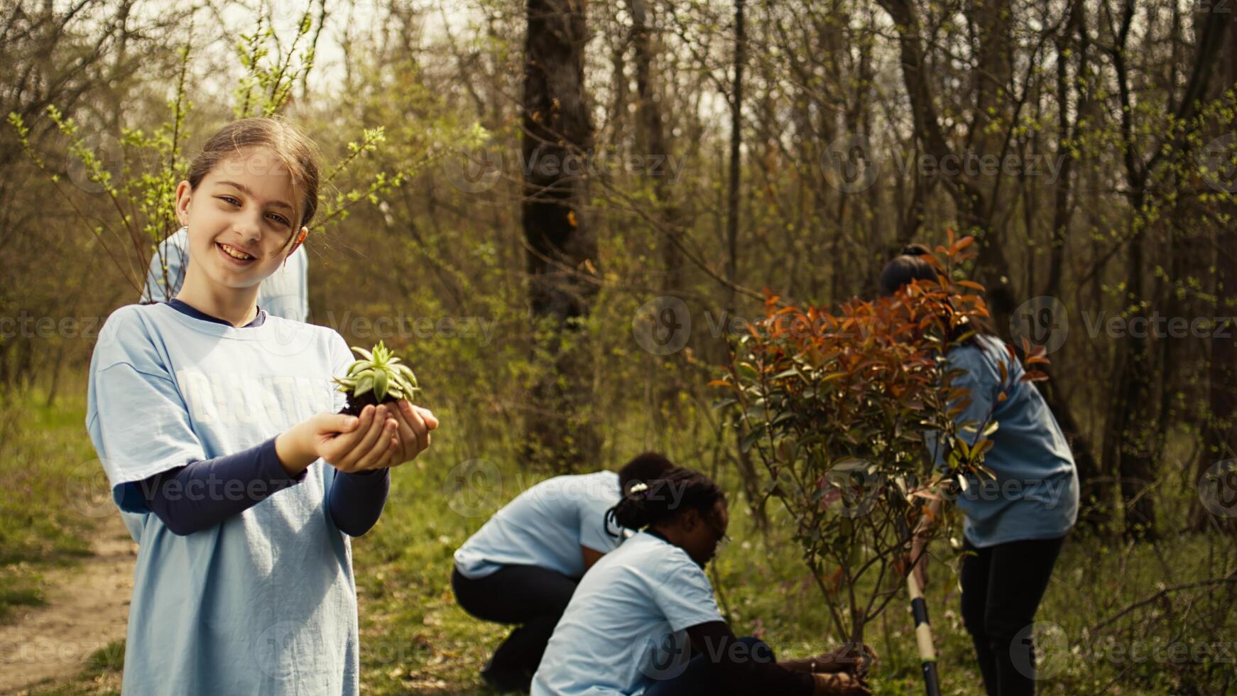 Little girl holding a small green sprout with natural soil in order to preserve forest habitat and protect the ecosystem. Child growing up with a dedication for environmental protection. Camera B. photo