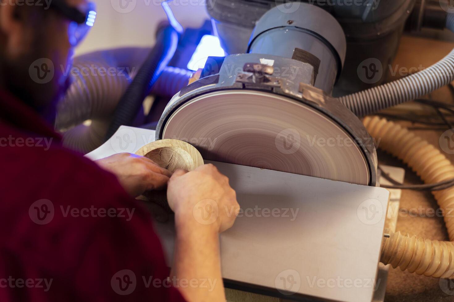 Artisan sanding wooden object on disc sander in assembling shop. Diy hobby enjoyer working in joinery, guiding wood against grinding machine rotating disc to create art photo