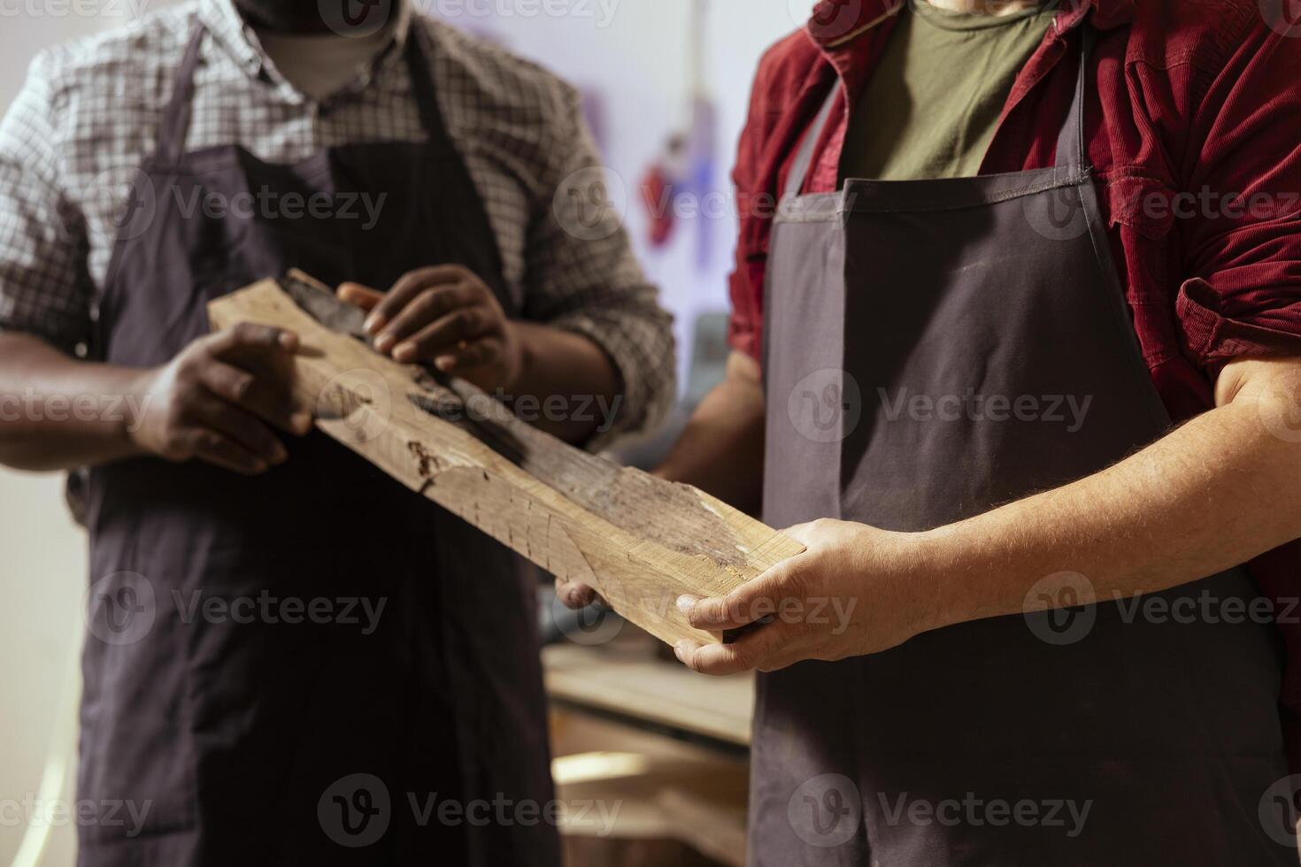Manufacturer and apprentice selecting high quality wood materials, ensuring they align with project requirements. Cabinetmaker and colleague doing quality assurance on lumber piece, close up shot photo
