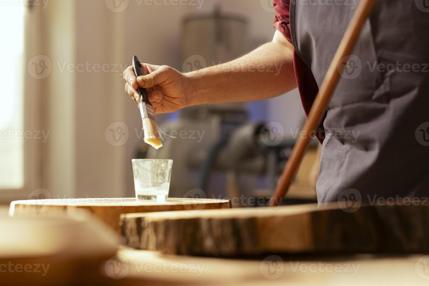 Cabinetmaker in assembly shop starting renovation project on timber block, applying lacquer on surface. Woodworking specialist coloring wood plank with paintbrush, enjoying diy hobby, close up photo