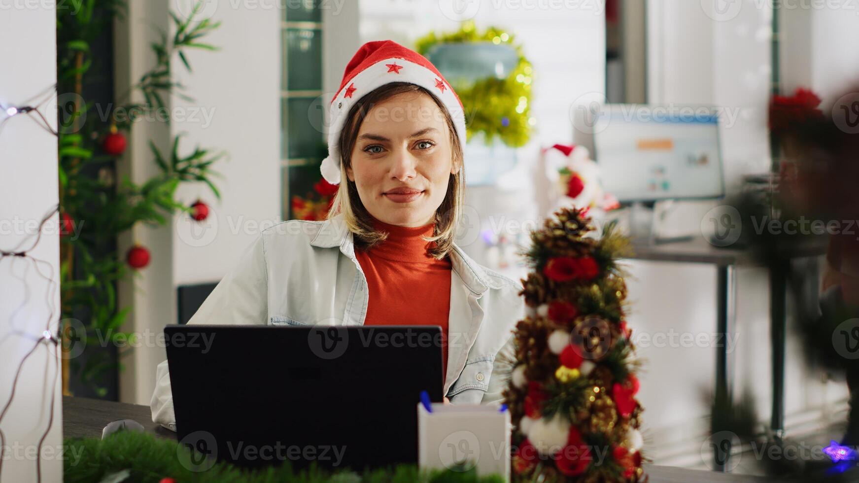 Close up portrait of bookkeeper in Christmas decorated office checking documents for accuracy. Employee solving tasks at computer desk in xmas ornate workspace during winter holiday season photo