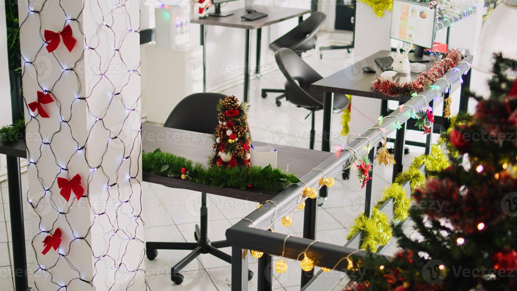 Zoom in on beautifully decorated Christmas pine tree placed in empty office. Xmas tree adorn with red bows and baubles in festive workplace filled with lights during winter holiday season photo