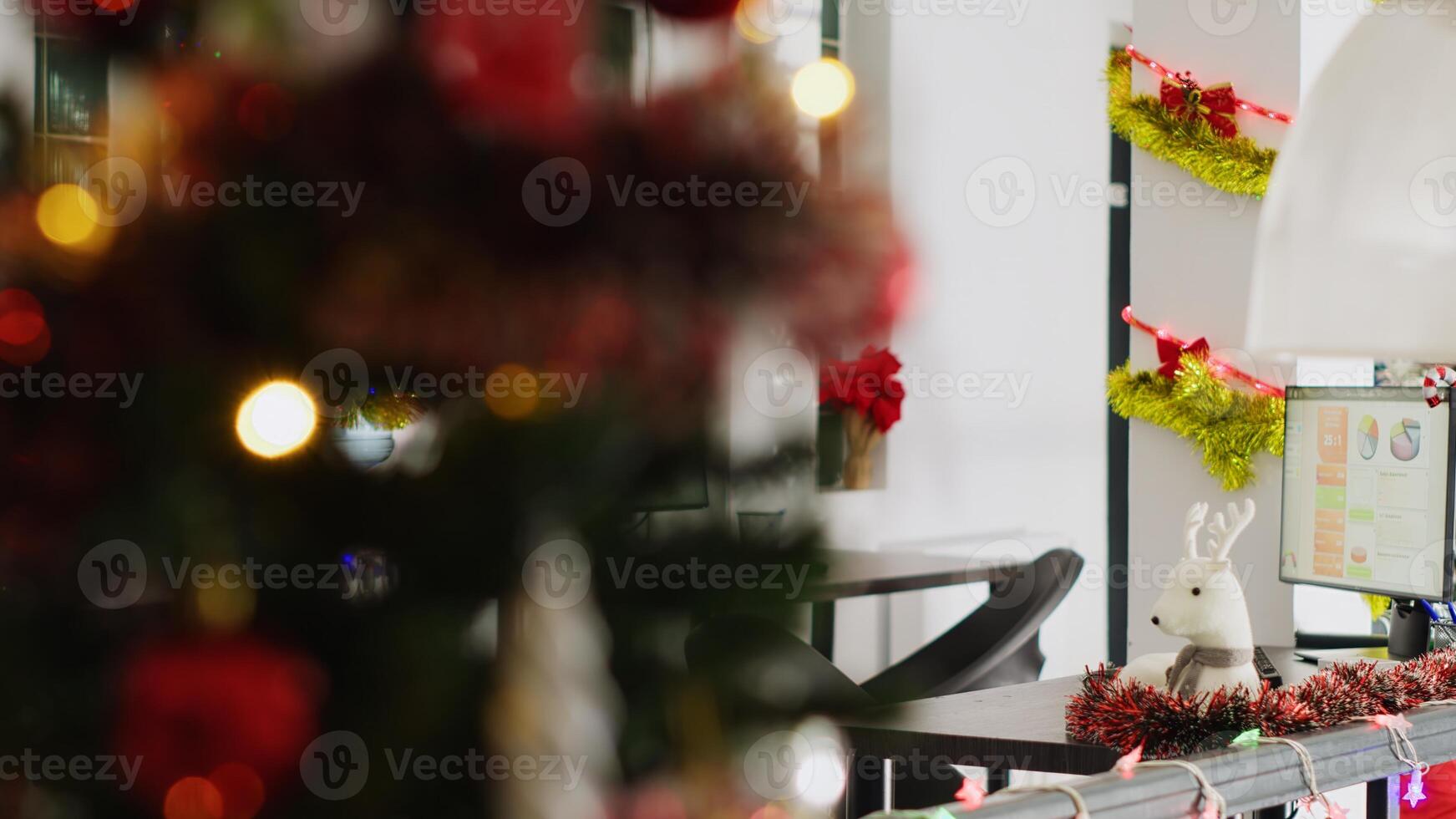 Empty festive ornate office with Christmas lights and Santa figurine. Business payroll reports on computer screens in xmas adorn workplace with no workers during winter holiday season photo