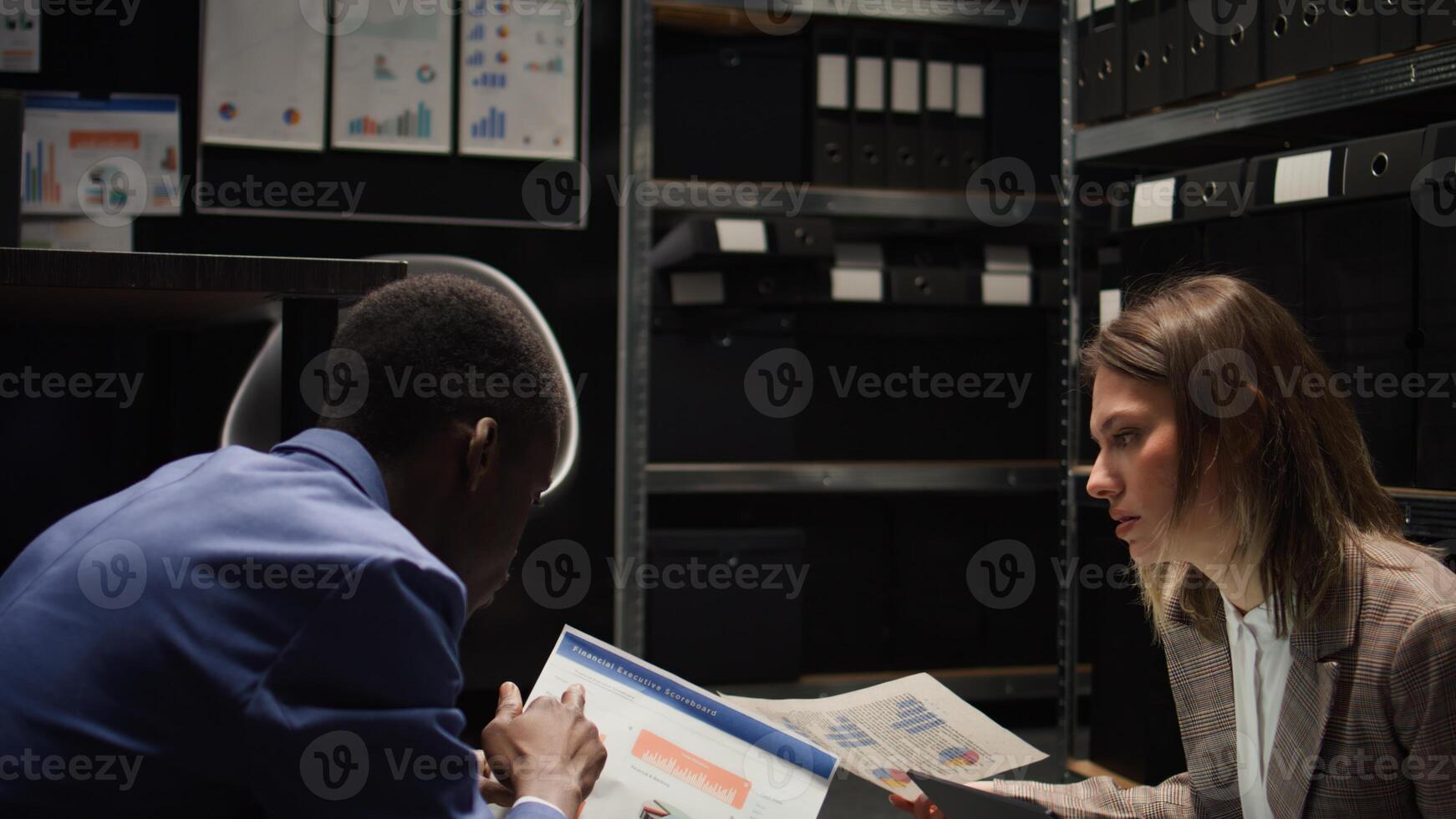 Seated on floor in incident room, african american investigator and caucasian policewoman look for clues and evidence. Female inspector with laptop, discussing criminal case with police officer. photo
