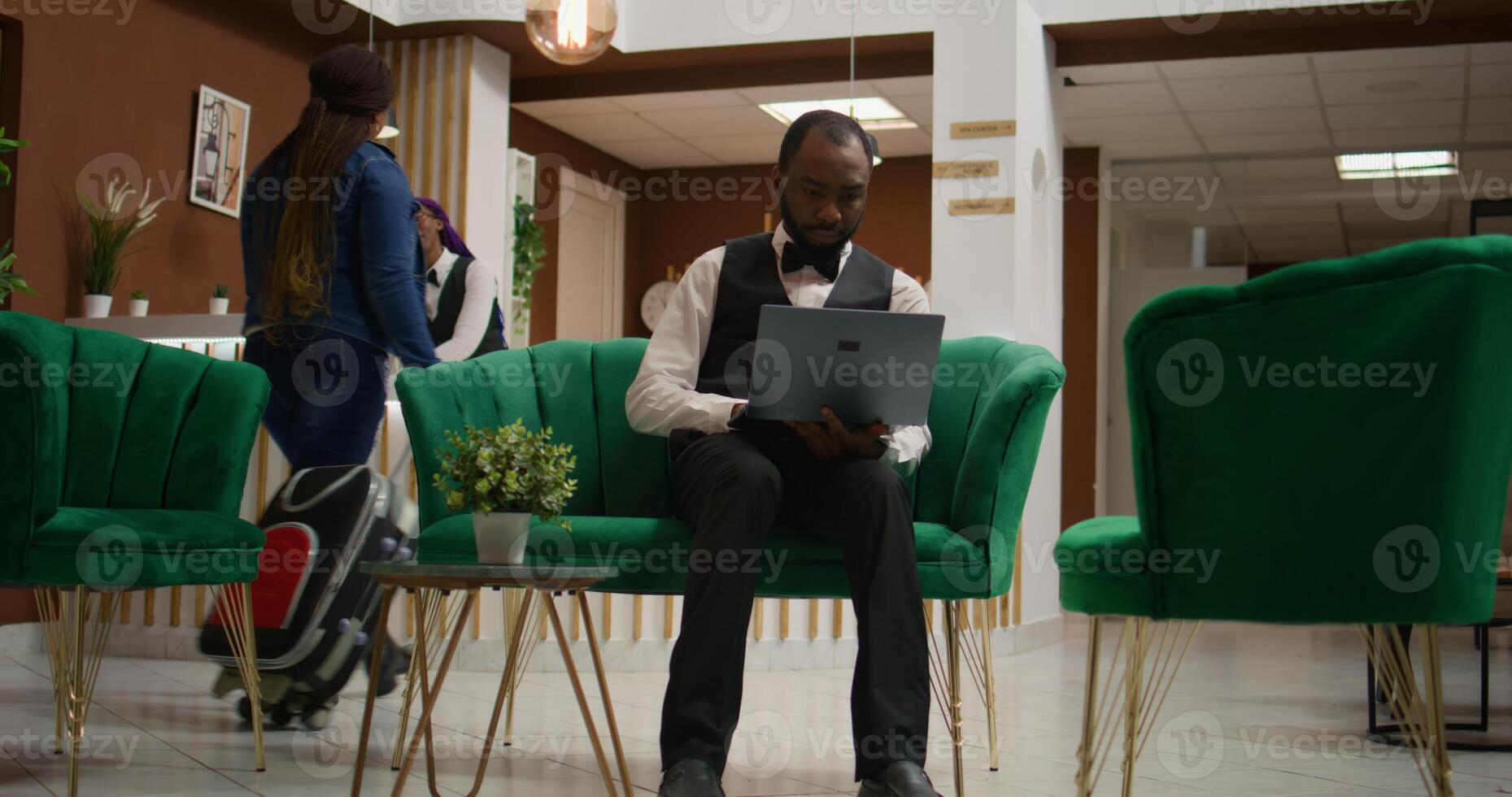 Hospitality industry employee. Bellhop processing data from registration forms in lounge area, hotel concierge making entry on list of guests to assign right rooms, clipboard notes. photo