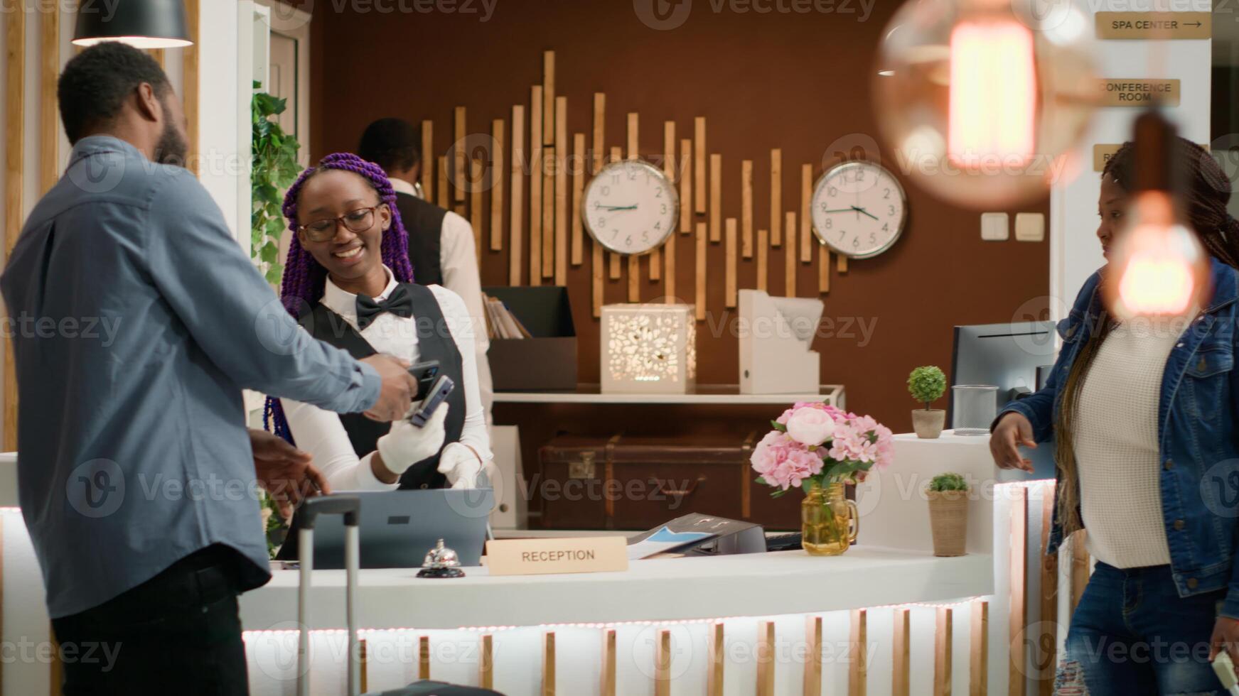 Guests leaving access key card at reception after amazing holiday, doing check out procedure and travelling home. African american people thanking hotel concierge for great service. Handheld shot. photo