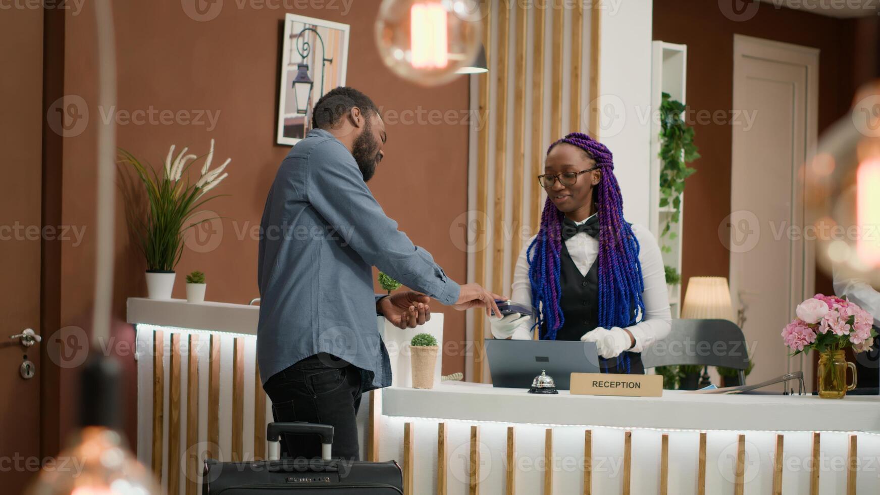 Traveller leaving resort after holiday trip, doing check out process and giving key card to woman employee. Content person ending vacation and showing respect to front desk reception staff. photo