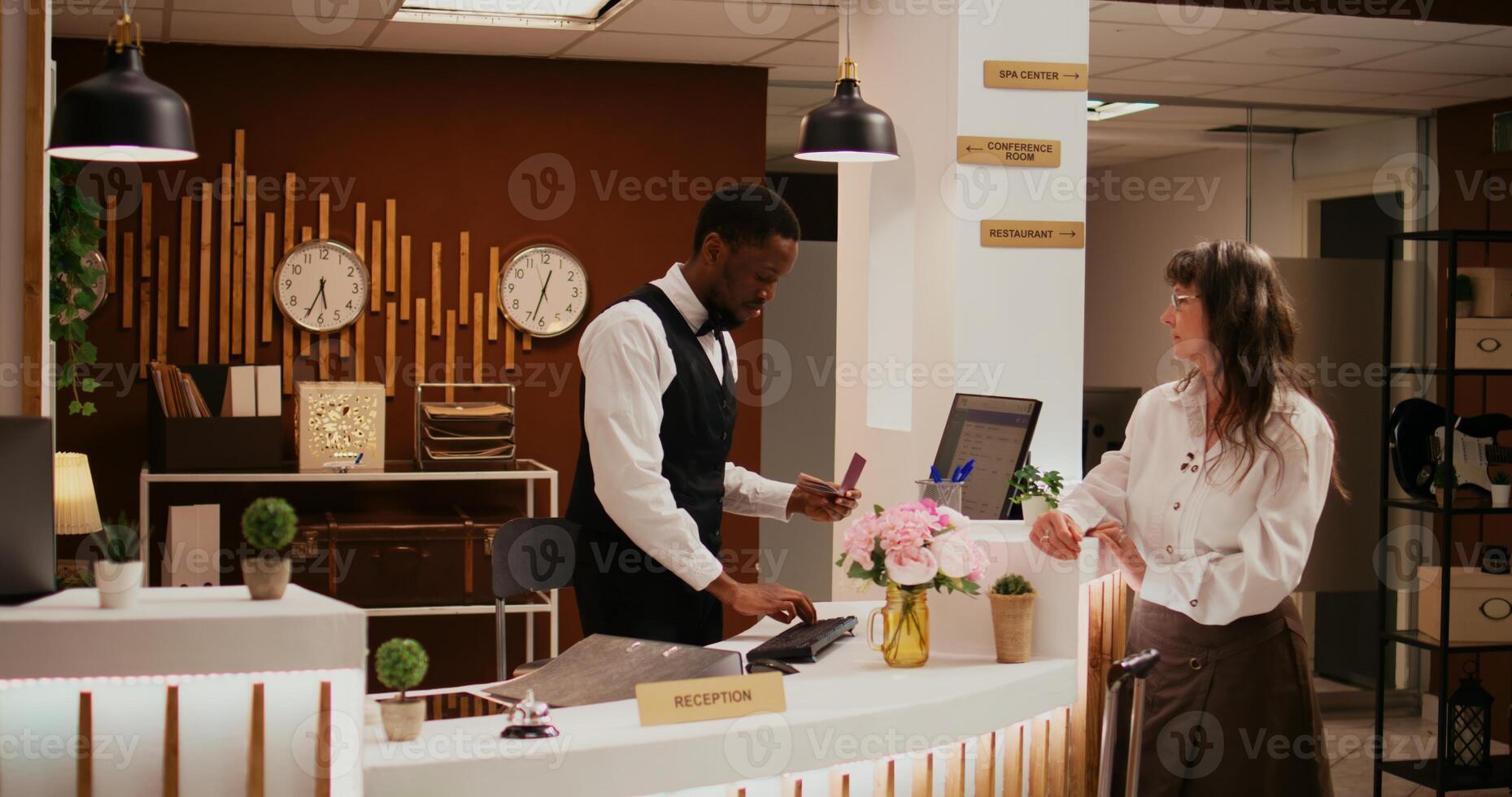 African american worker verifying passport id at front desk before registering for room reservation, concierge services. Staff assisting old woman with check in, hospitality industry. photo