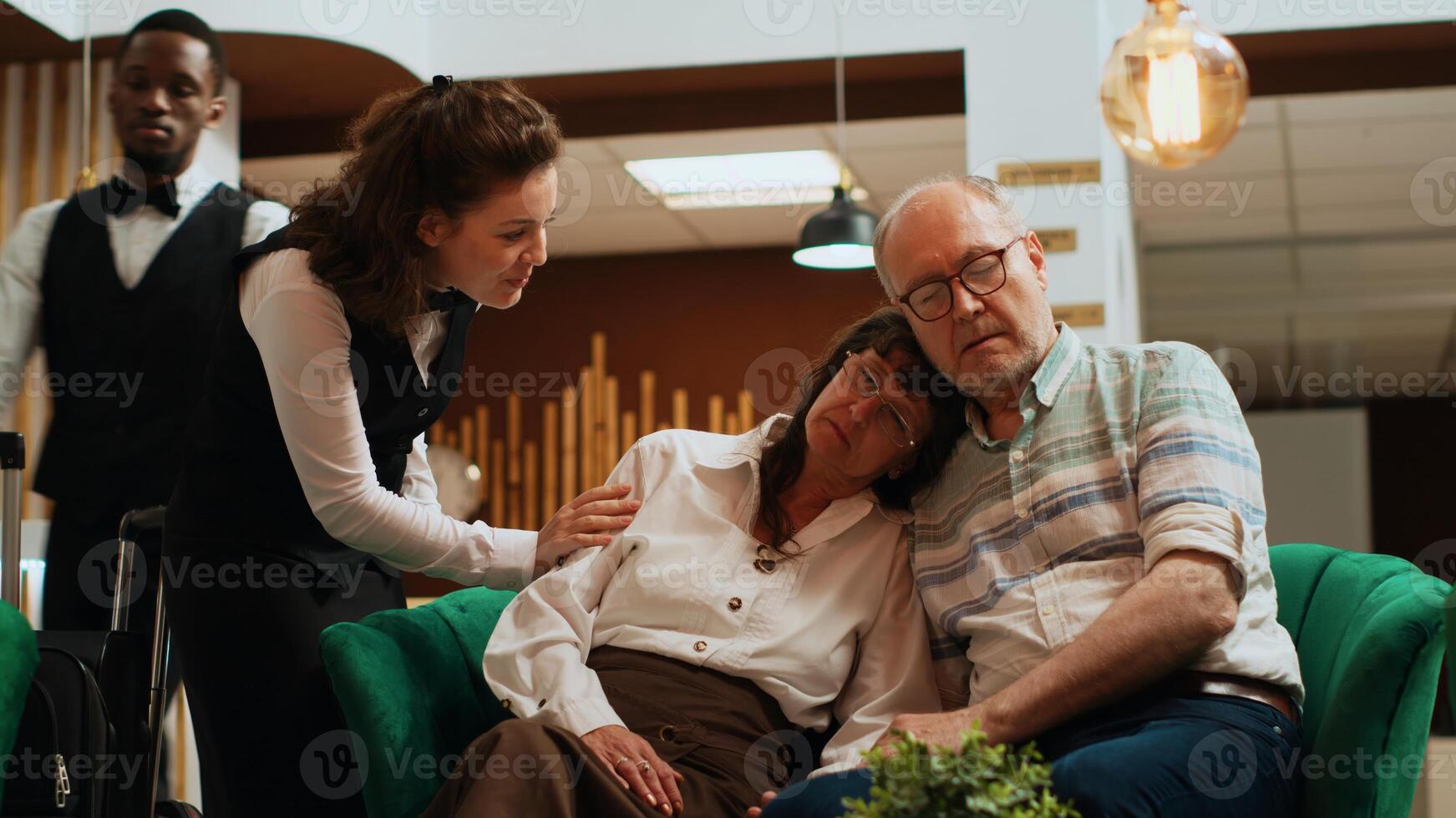 Elderly people sleeping on each other at hotel reception, waiting to see room reservation and start holiday. Retired exhausted couple dealing with jetlag after international flight. Handheld shot. photo