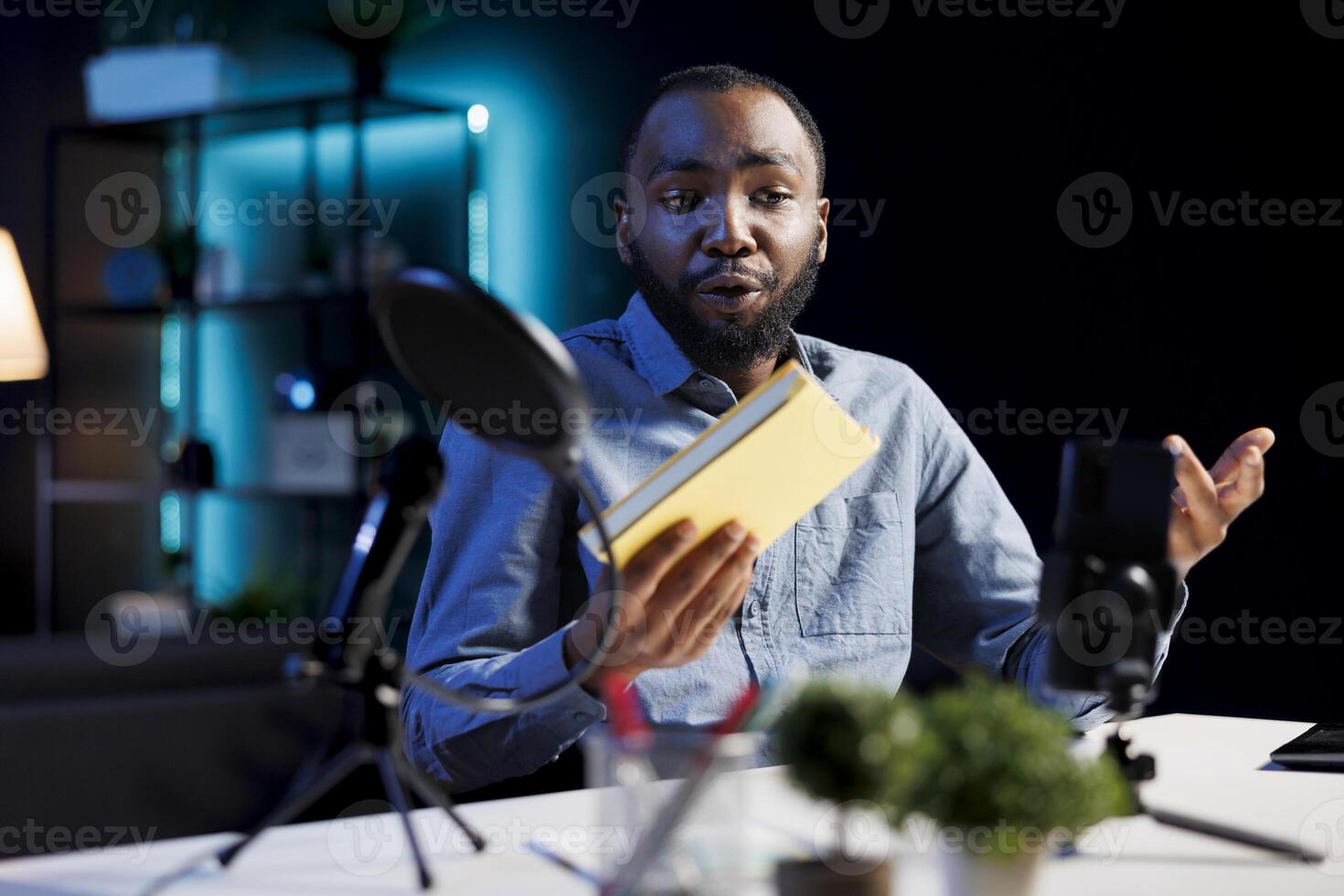 Disappointed african american content creator films review of book, browsing through pages, unimpressed by writing style. Online star giving low rating feedback to new novel release photo