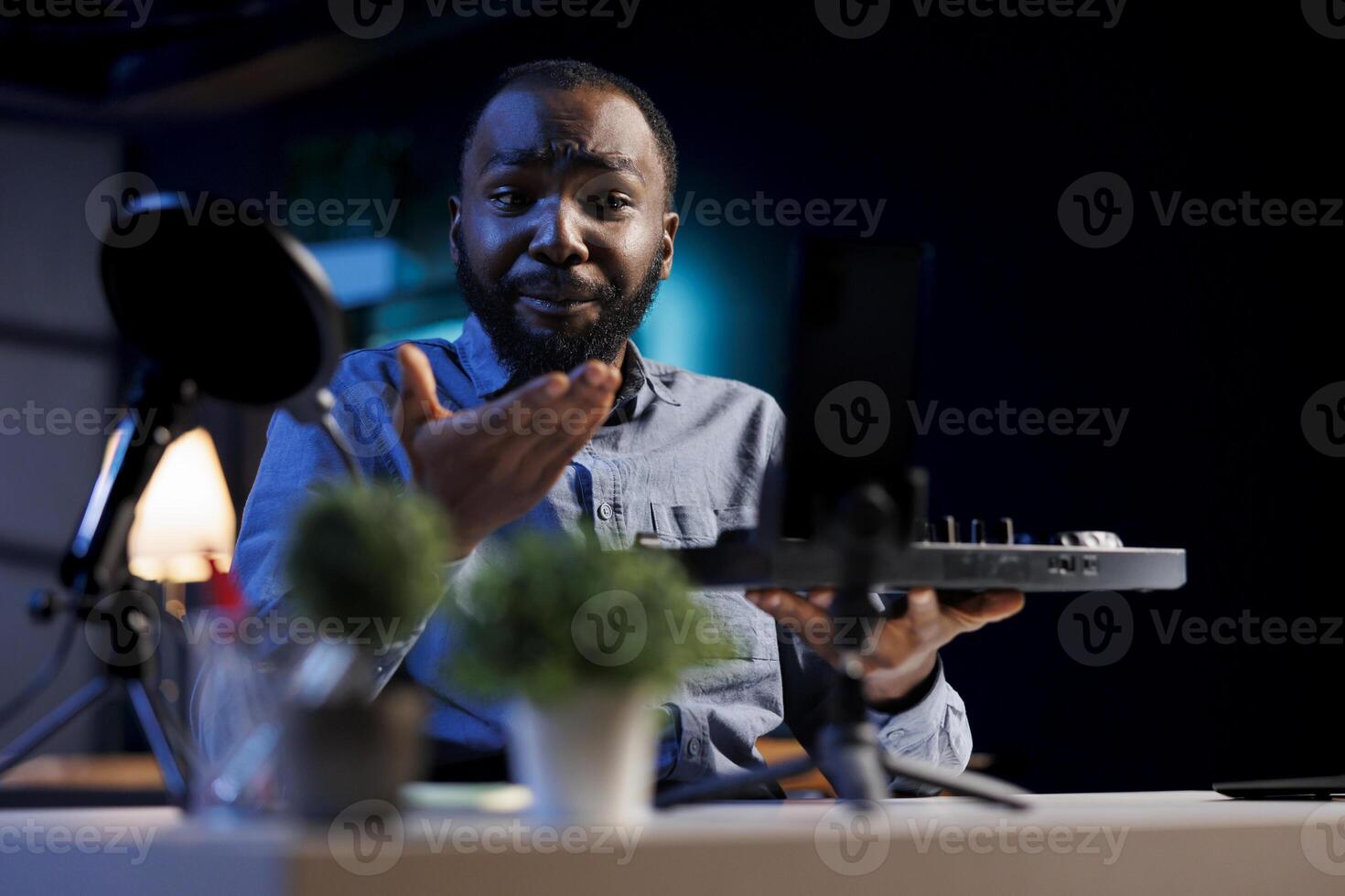 Content creator playing around with stereo sound mixer, showcasing his skills, entertaining audience. Trending influencer mixing on DJ turntables, doing music production tutorial photo