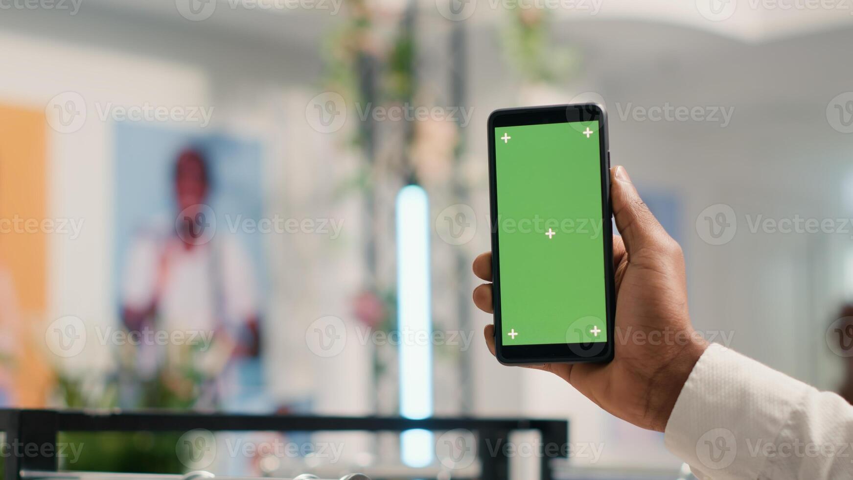Close up shot of client holding green screen smartphone in premium clothing store, looking at online products. Customer with green screen mobile phone in fashion boutique doing internet shopping photo
