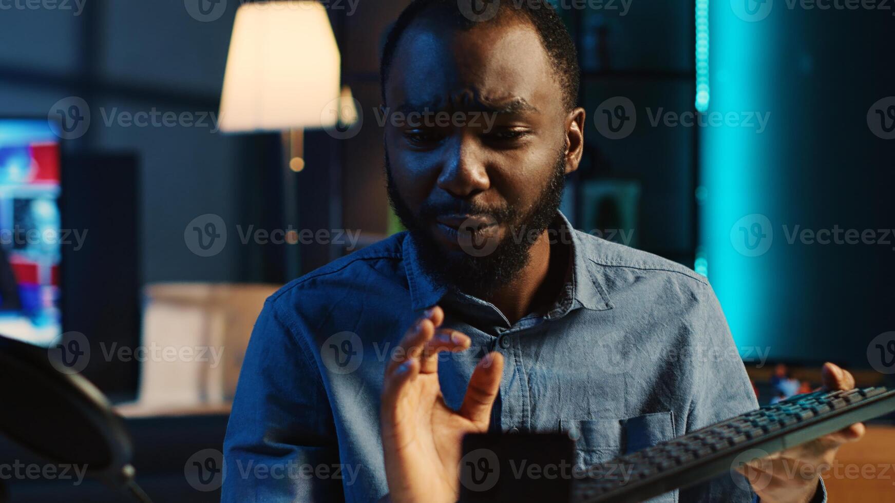 African american technology internet star filming review of newly released wireless keyboard, greeting audience and presenting them feedback about typing experience, doing endorsement photo