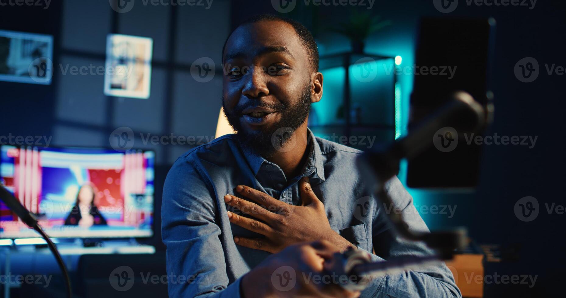 BIPOC content creator using selfie stick smartphone, doing for fans showing his cozy apartment studio. Media star talking with audience during online stream using mobile phone camera photo