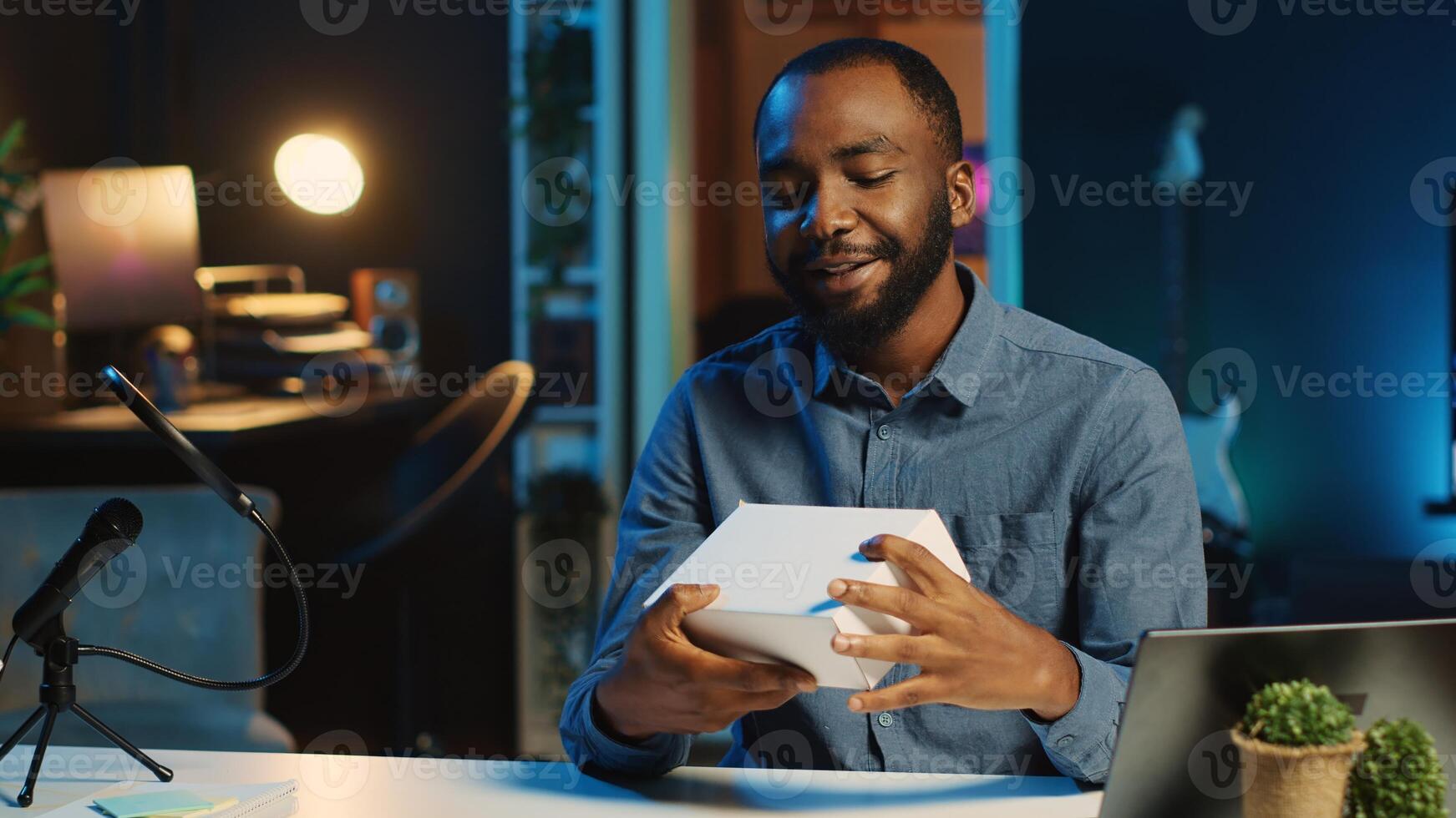 BIPOC tech content creator filming technology review of newly released smartphone, unboxing it and presenting parameters to audience. Internet star showing phone to subscribers photo