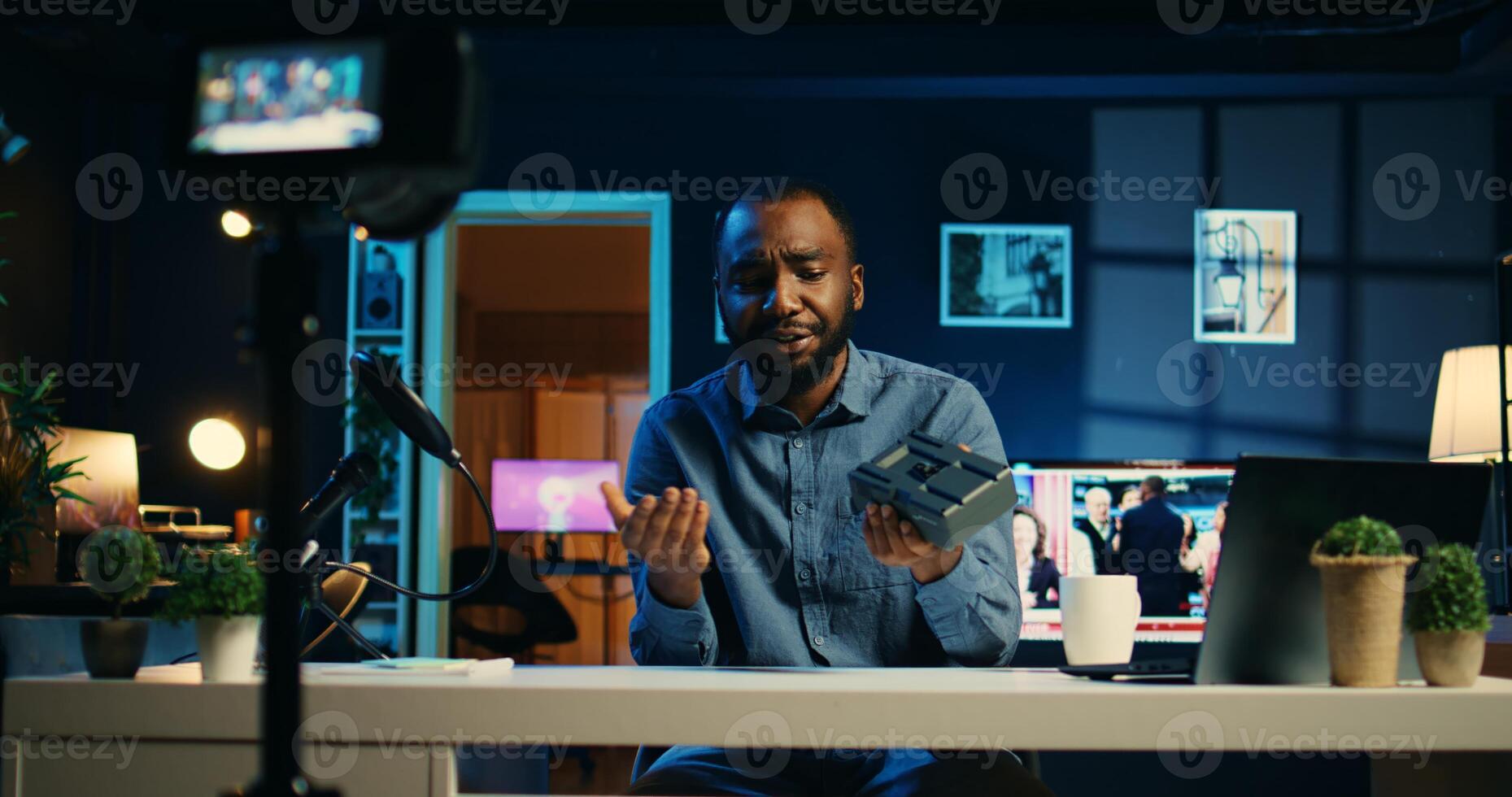 African american content creator filming technology review of newly launched V mount battery, unboxing it and presenting to audience. Online star showing charging device to viewers photo