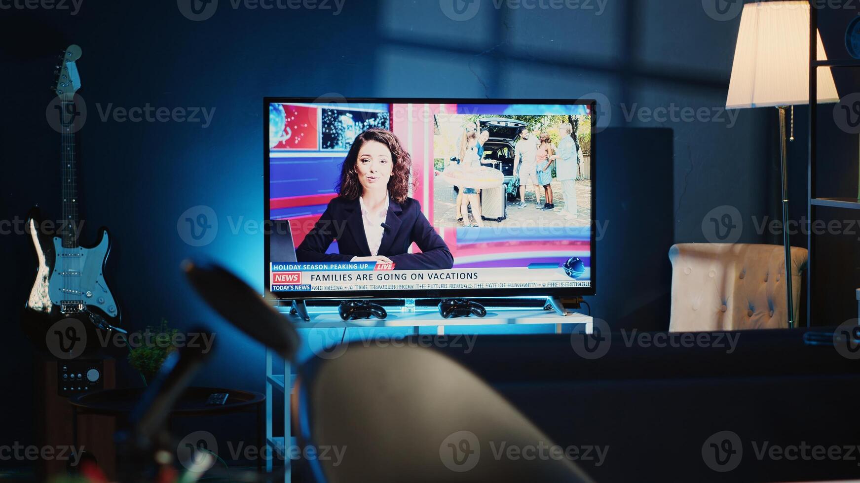 TV left open at night in cozy dimly lit apartment showing broadcast of Black Friday news story. Home entertainment system showing television reports in living room illuminated by lamp shade photo