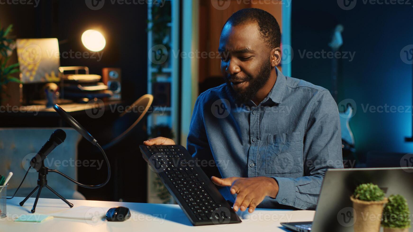 Content creator in dimly lit living room using camera to film keyboard review for online streaming platforms. Online star hosts technology internet show, unboxing peripherals photo