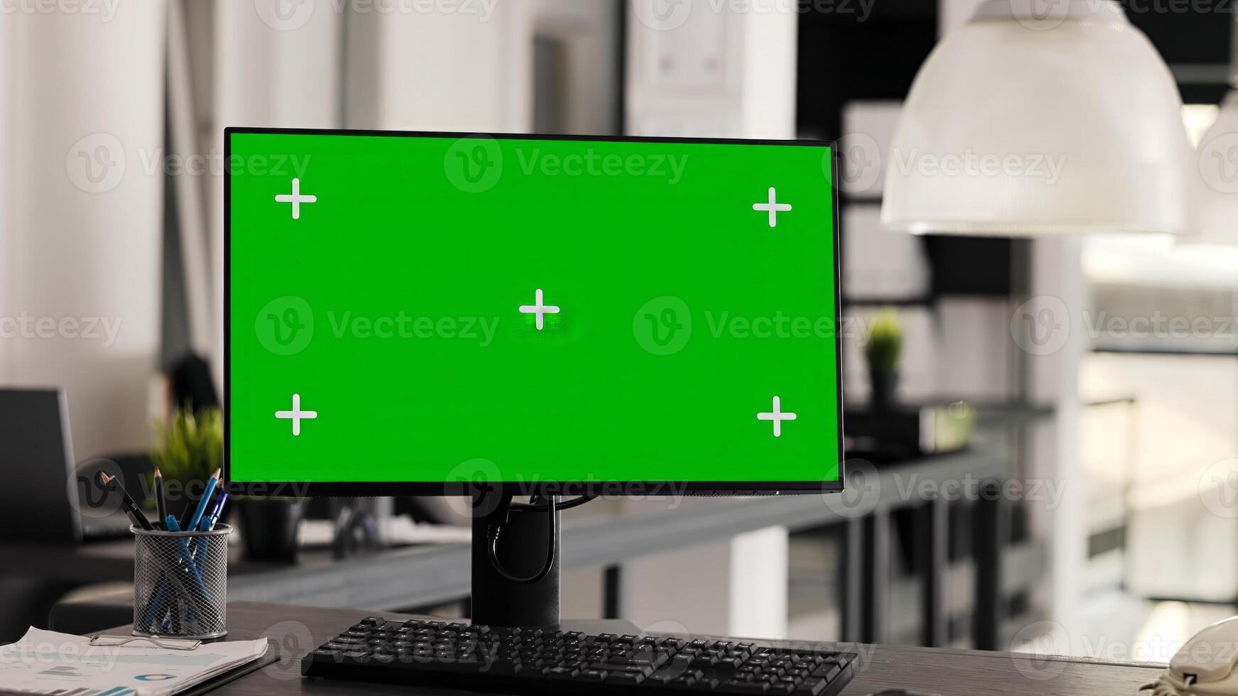 Empty workstation with computer running greenscreen on monitor, showing blank chromakey template in coworking space. Desk in open floor plan office with pc and isolated copyspace display. photo