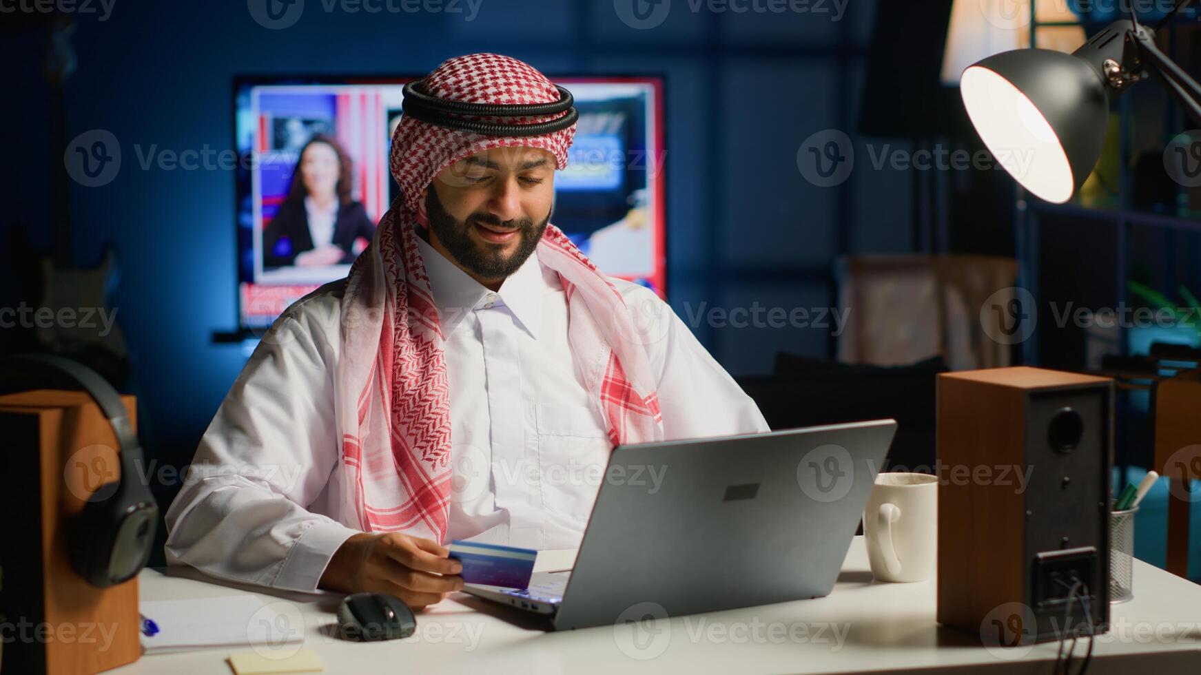Arabic man doing online shopping, carefully typing credit card information on computer. Muslim person adding payment method on website while in cozy stylish warm home at night photo