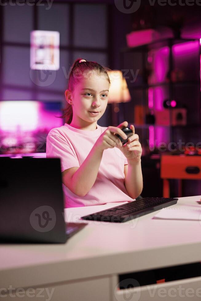 Happy girl films assessing Bluetooth mouse, talking about components used. Young media star shoots wireless computer peripheral review for online channel, pleased with materials quality photo