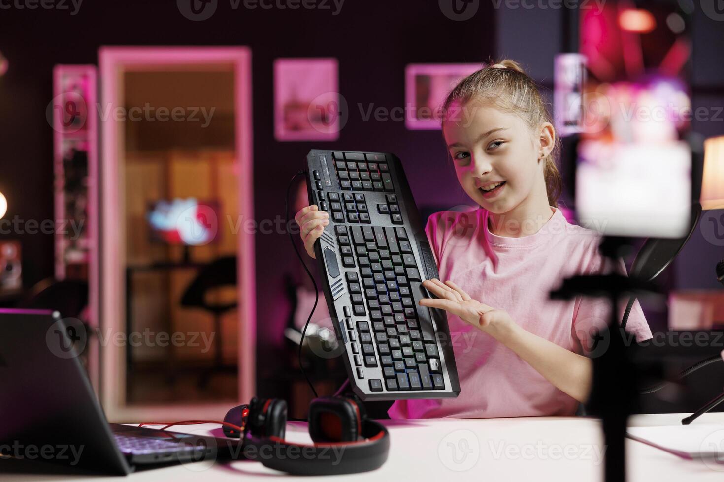 Joyful kid showing viewers mechanical keyboard received from sponsoring brand to promote it. Gen Z online show host advertising wired gaming computer peripheral from partnering company photo