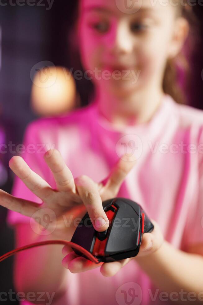 Close up shot on gaming mouse received by kid from sponsoring brand to promote it. Focus on wired computer peripheral advertised by young child in blurry background doing influencer marketing photo