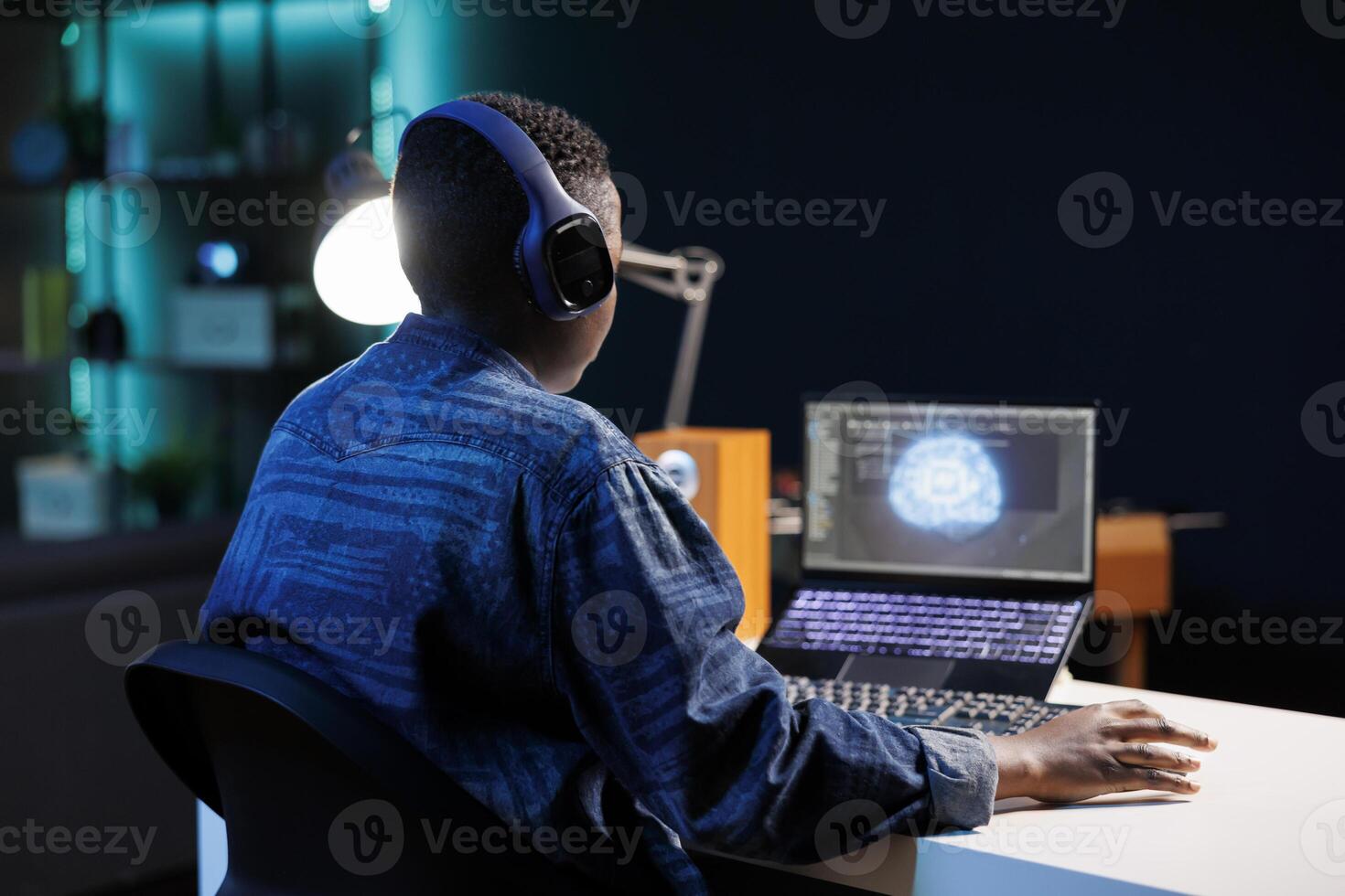 African American programmer with wireless headphones is working on her laptop. Black woman listening to music while using code and artificial intelligence to manage and monitor a neural network. photo