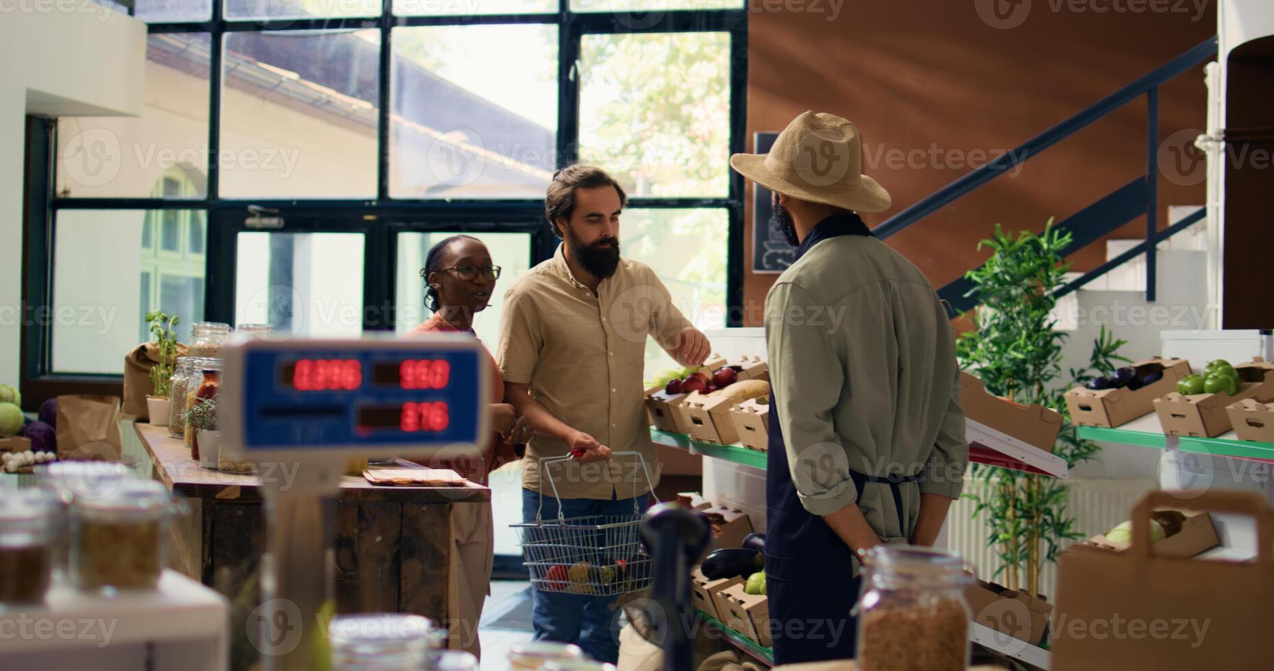 Couple asking vendor about fresh produce in organic zero waste store, storekeeper recommending fruits and veggies harvested from garden. Merchant presenting chemicals free food. photo