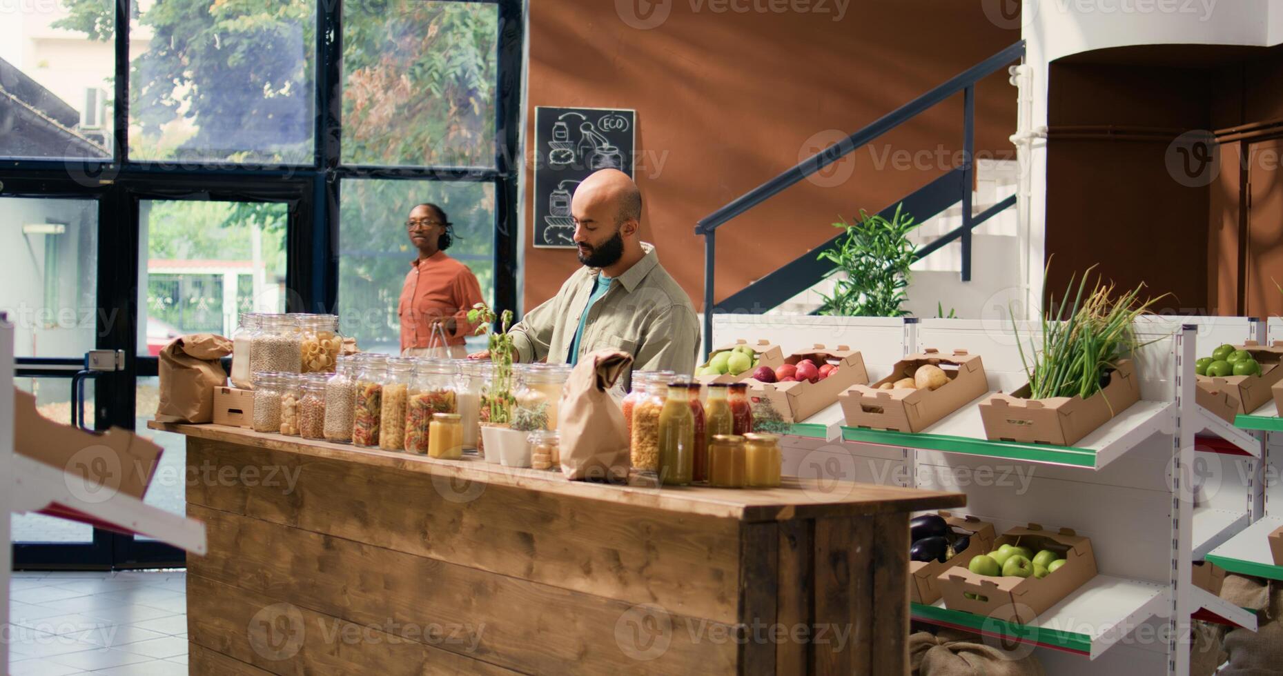 Client in sustainable market store looking at pasta or grains stored in reusable glass containers, local neighborhood zero waste shop. Buyer doing grocery shopping for organic chemicals free produce. photo