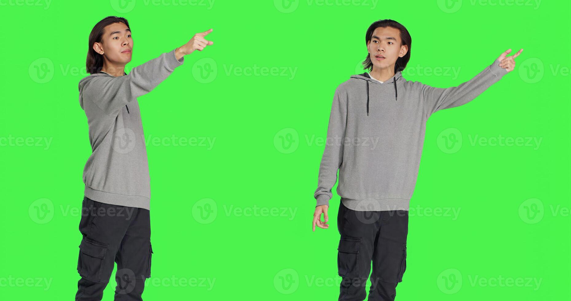 Model indicating left or right directions in studio, pointing to both sides and recommending another path. Asian young guy advising people to go this way using index fingers, greenscreen. photo