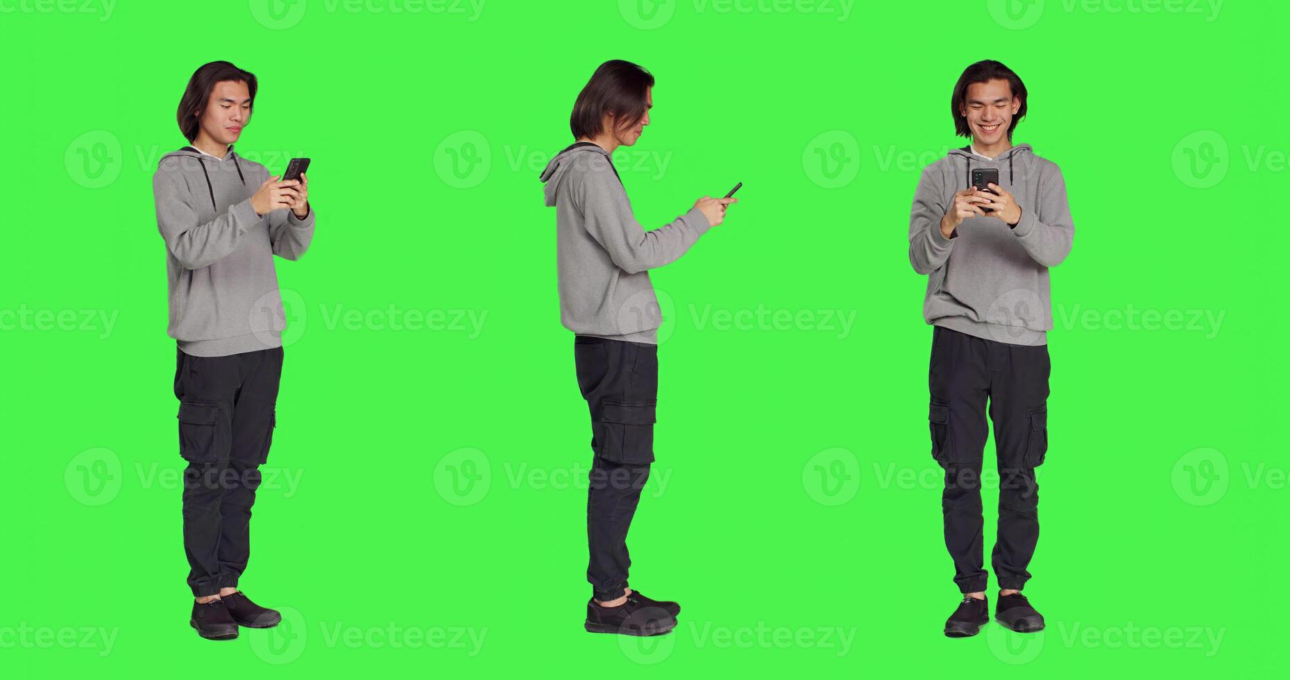 Adult texting messages on phone standing over greenscreen background, using social media app to chat remotely with friends. Asian joyful person messaging on modern smartphone. photo