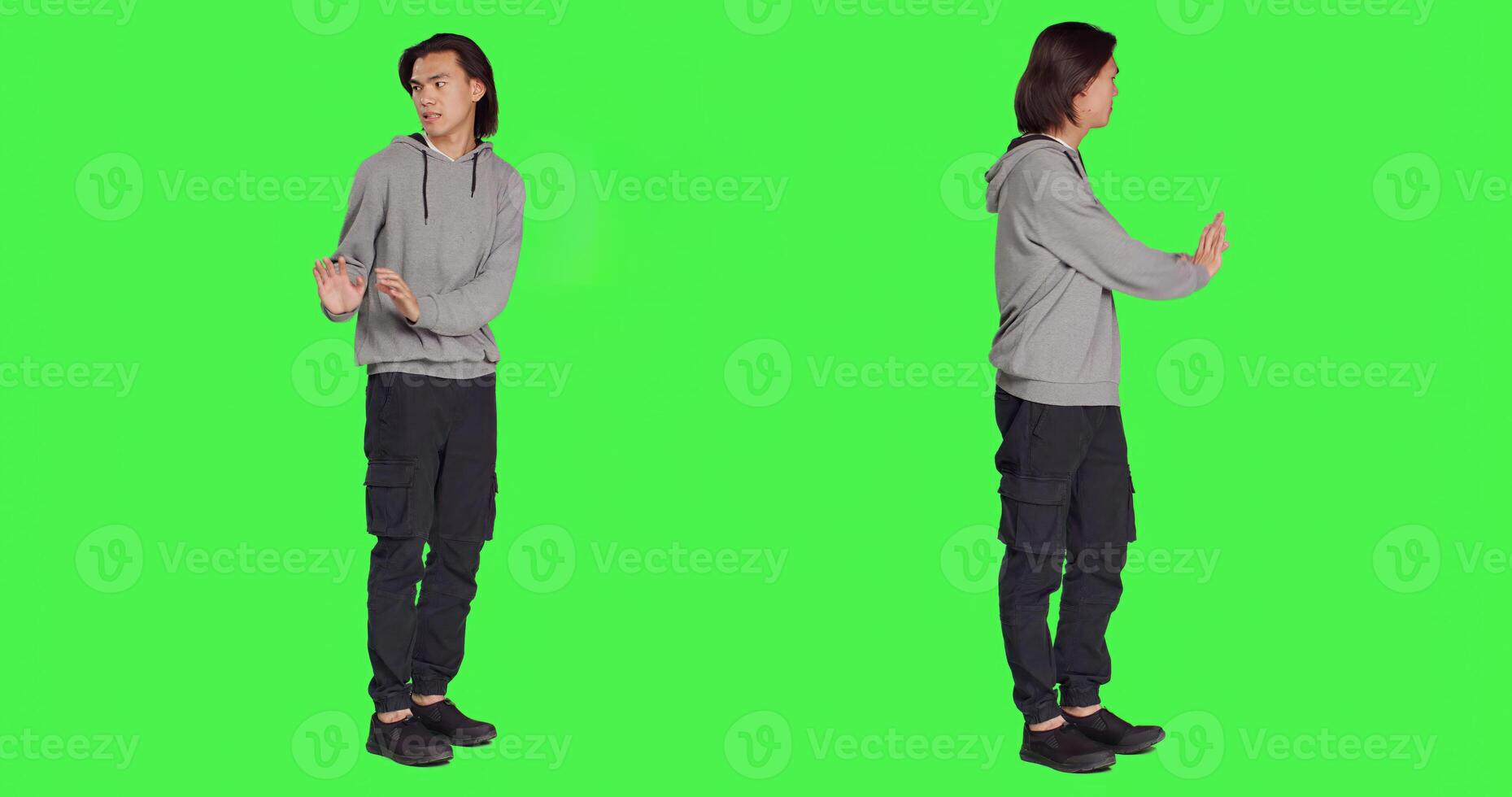 Person pretending to push thing aside, expressing rejection or denial in studio. Young adult mimicking refusal over isolated full body greenscreen background, stop symbol on camera. photo