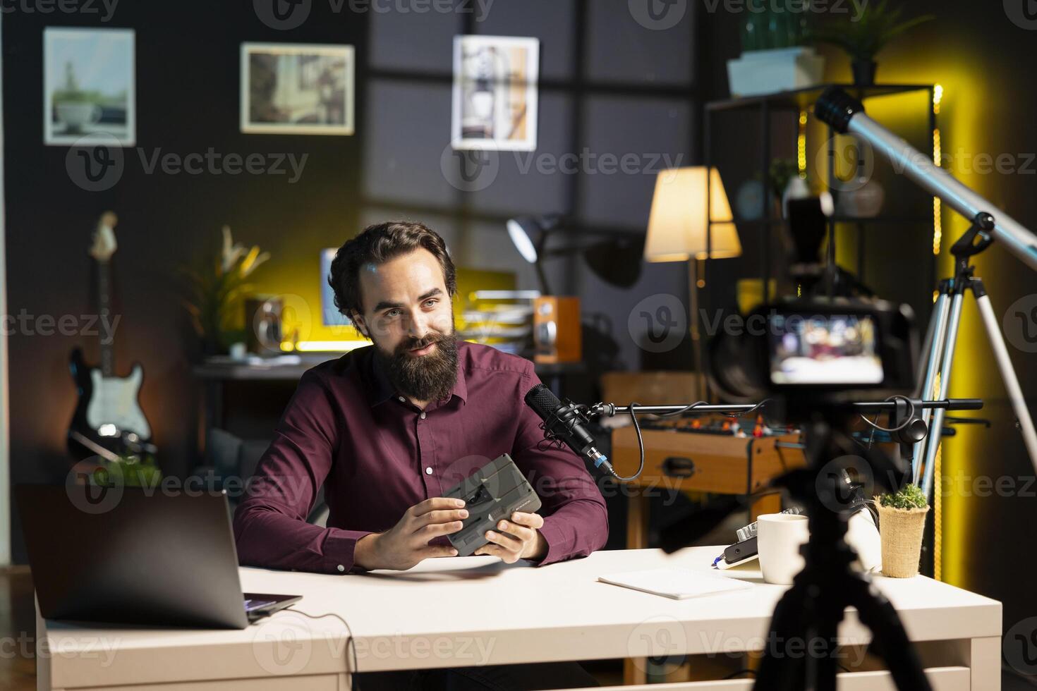 Tech guru presenting V mount battery, filming technology review using professional camera and mic. Media star showcasing charging device specs, recording with specialized equipment photo